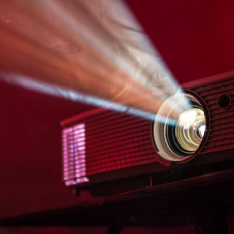 Red projector over red background projecting a beam of light.